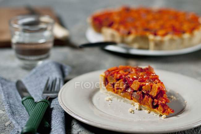 Potato tart with tomatoes and pepper on white plate over table — Stock Photo