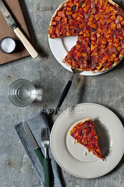 Kartoffeltarte mit Tomaten und Paprika auf Tellern über dem Tisch — Stockfoto