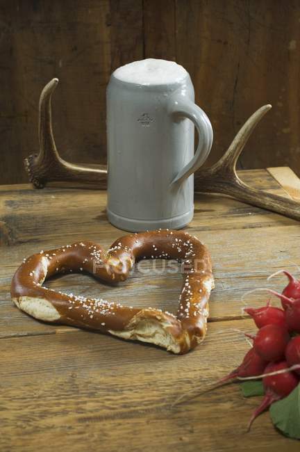 Heart-shaped pretzel with radishes — Stock Photo
