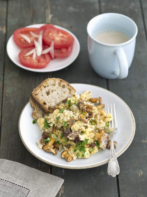 Scrambled eggs with mixed wild mushrooms on white plate with fork — Stock Photo