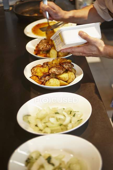 Cropped view of person serving dishes on counter — Stock Photo