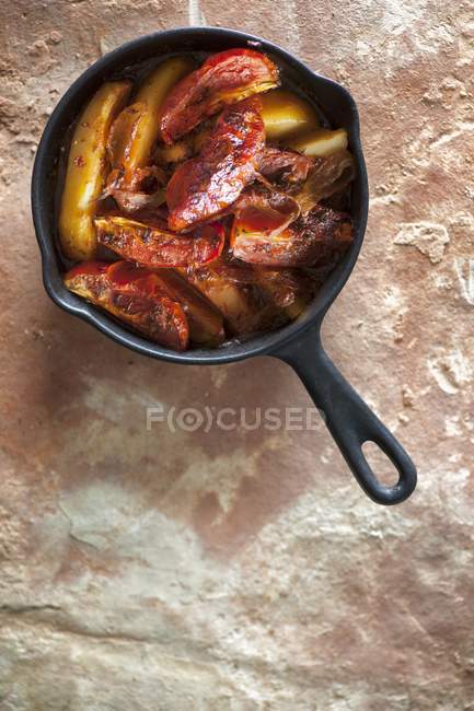 Baked tomatoes and potatoes in pan on wooden surface — Stock Photo
