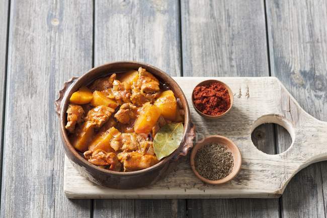 Chicken and potato goulash in a ceramic bowl over wooden surface — Stock Photo