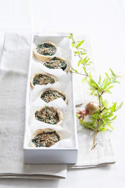 Mini quiche spinaci su piatto bianco su asciugamano su sfondo bianco — Foto stock