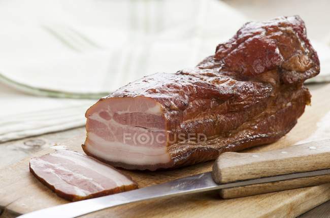 Smoked bacon on wooden chopping board — Stock Photo