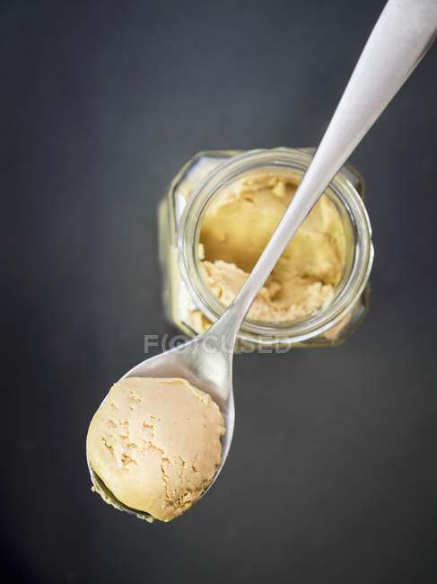 Gros plan vue du dessus de beurre de noix de cajou maison sur cuillère et dans un bocal — Photo de stock
