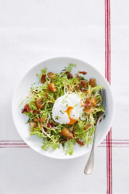 Вид яиц-пашот на салате с беконом и гренками — стоковое фото