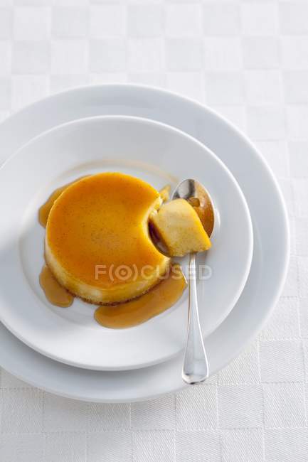 Caramel pudding with piece on spoon — Stock Photo