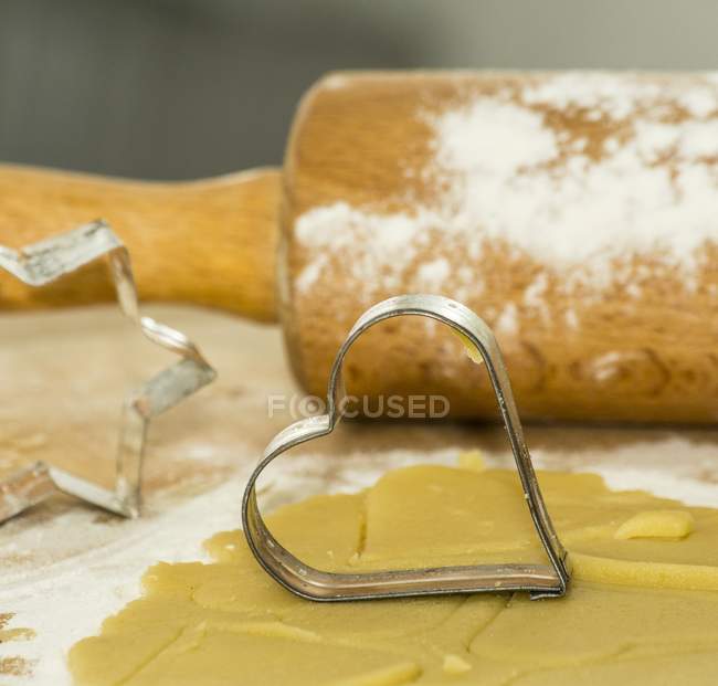 Closeup view of cookie cutters with rolling pin and biscuit pastry — Stock Photo