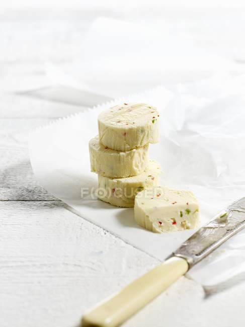 Vista close-up de quatro fatias de pimenta e manteiga de limão com uma faca em papel à prova de gordura — Fotografia de Stock