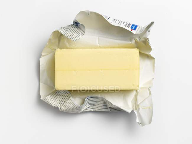 Vista superior de una palmadita de mantequilla sin envolver en su envoltura — Stock Photo