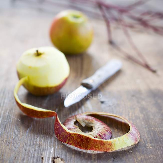 Apples with peel and fruit peeler — Stock Photo