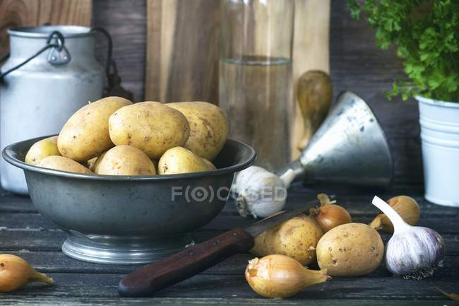 Potatoes in metal bowl with onions and garlic — Stock Photo