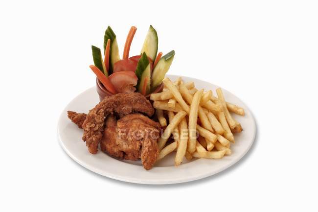 Куриные наггетсы с чипсами и овощами на белой тарелке — стоковое фото