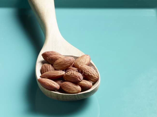 Unshelled almonds on wooden spoon — Stock Photo