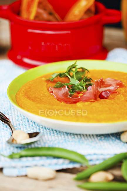 Zuppa di zucca con pancetta ed erbe su piatto bianco sopra asciugamano con cucchiaio — Foto stock