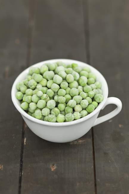Cup of frozen green peas — Stock Photo