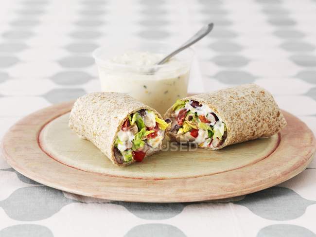 Three bean wraps with sour cream and a chive dip on wooden desk — Stock Photo