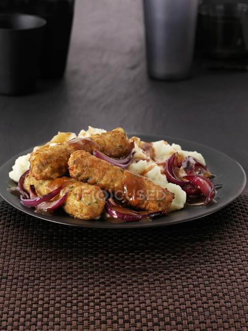 Salsichas vegetarianas com purê de batatas e molho em prato preto — Fotografia de Stock