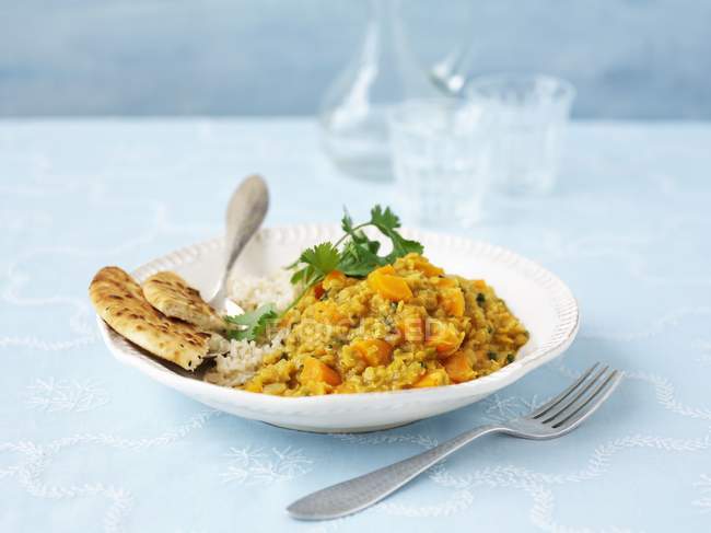 Curry lentilha vegetariana na placa branca sobre a superfície azul com garfo — Fotografia de Stock