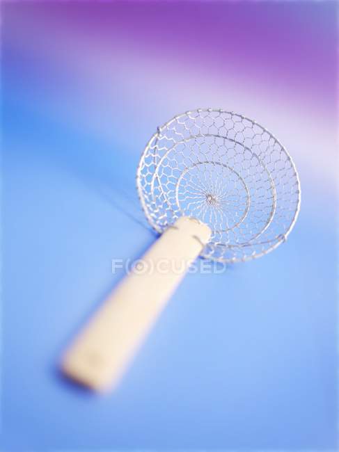 Closeup view of a Chinese fry sieve on blue surface — Stock Photo
