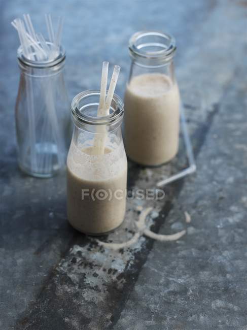 Молочний коктейль з горіхами в банках з соломинками — стокове фото
