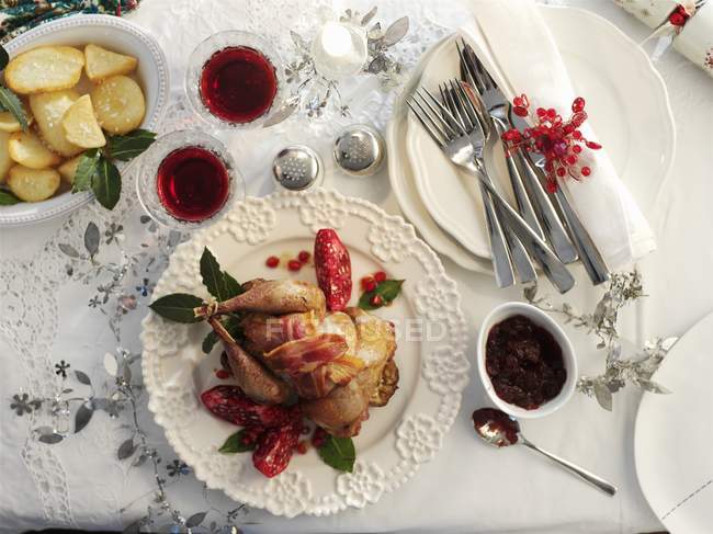 Top view of roasted pheasant wrapped in bacon with pomegranate seeds and potatoes — Stock Photo