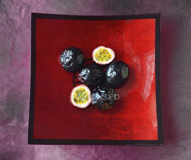 Passion fruits in red fruit bowl — Stock Photo