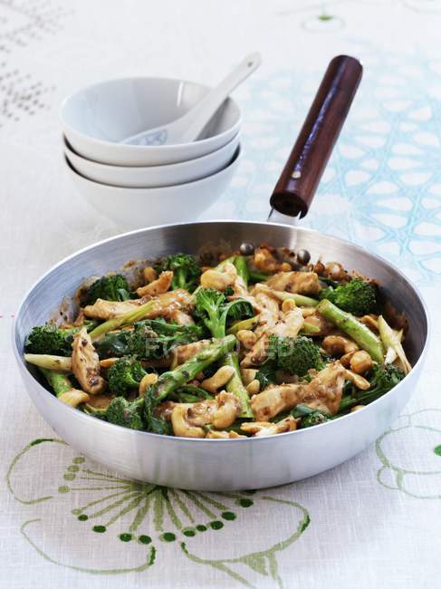 Chicken stir fry with broccoli and cashew nuts in frying pan on tablecloth — Stock Photo