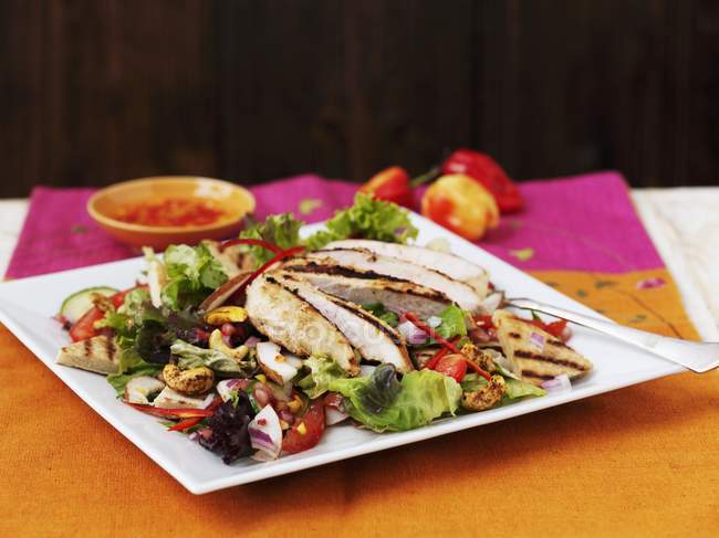 Овощной салат с курицей и орехами кешью на белой тарелке — стоковое фото