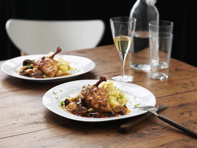 Hühnchen mit Brandy-Sauce, Kartoffelpüree und Lauch auf weißen Tellern über der Holzoberfläche — Stockfoto