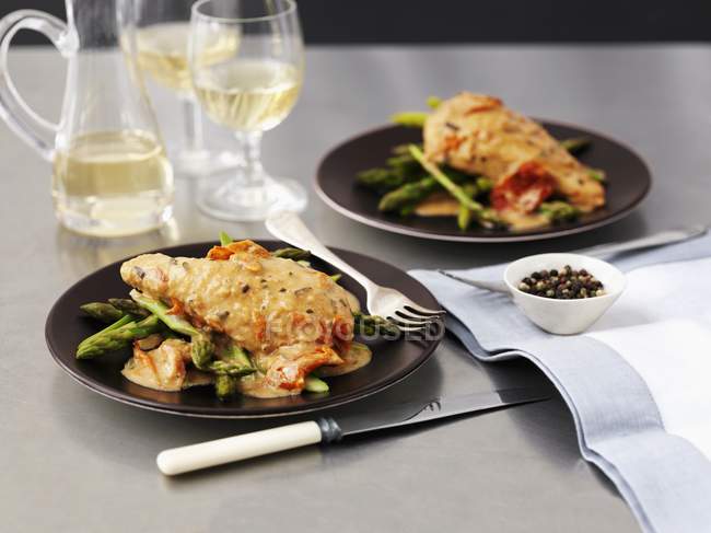 Pollo in salsa di vino bianco e asparagi su piatti neri in tavola — Foto stock