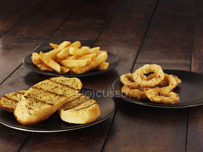 Garlic bread on black plates — Stock Photo