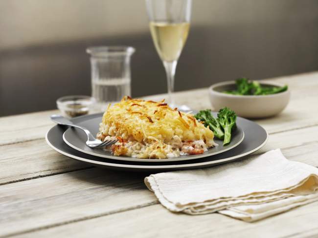 Torta mista di pesce con broccoli e vino su piatti neri a tavola — Foto stock