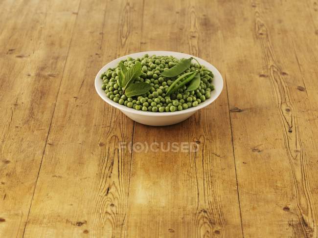 Інгредієнти для горохового і м'ятного супу на білій тарілці над дерев'яною поверхнею — стокове фото