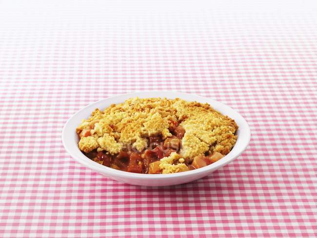 Closeup view of rhubarb Crumble in bowl on checkered cloth — Stock Photo