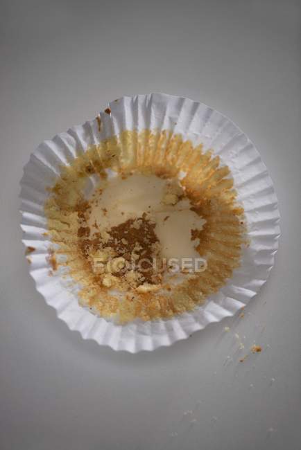 Closeup view of a used muffin case on white surface — Stock Photo