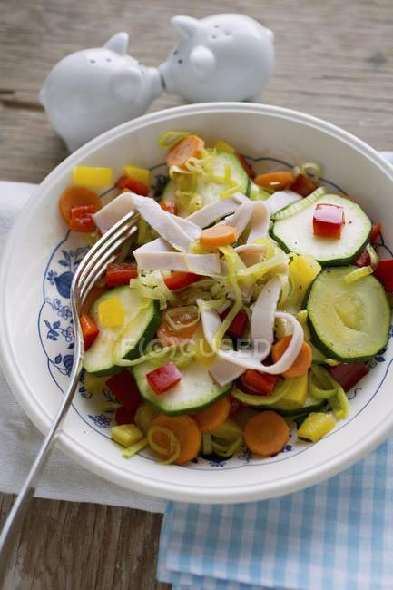 Gebratenes Gemüse mit Putenstreifen auf weißem Teller mit Gabel — Stockfoto