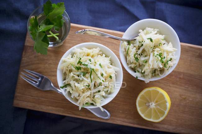 Kohlrabi-Salat mit Zitrone in weißen Schalen über Holztisch — Stockfoto