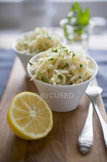 Kohlrabi salad with lemon in white pots over wooden desk — Stock Photo