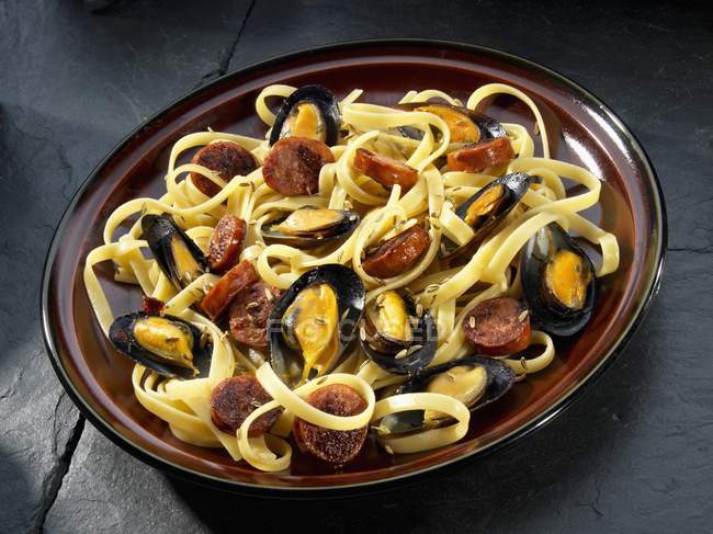 Mussels with sausage on pasta — Stock Photo