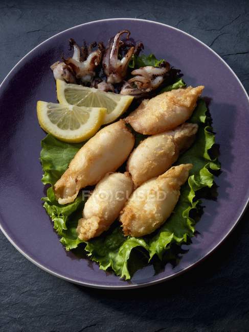 Nahaufnahme gebratener Tintenfischröhrchen mit Zitronen — Stockfoto