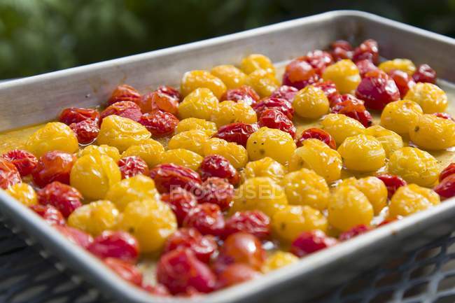 Tomates cherry rojos y amarillos asados en bandeja para hornear - foto de stock