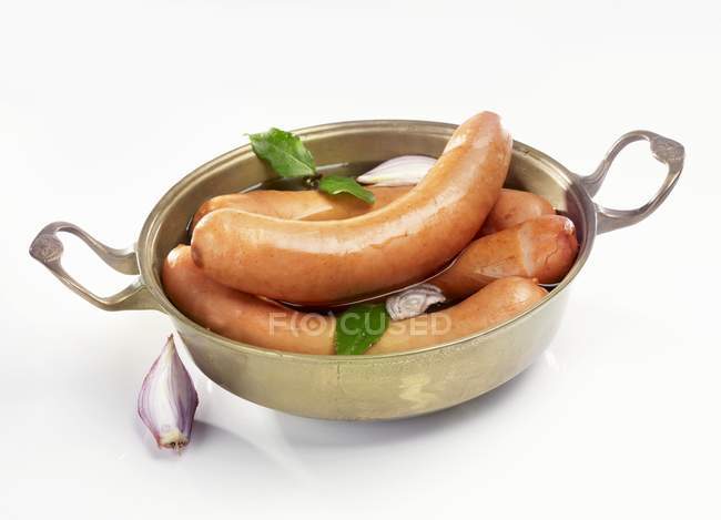 Sausages with onions and bay leaves — Stock Photo