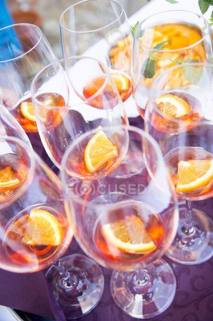 Vista elevada de Aperol en copas de vino con rodajas de naranja - foto de stock