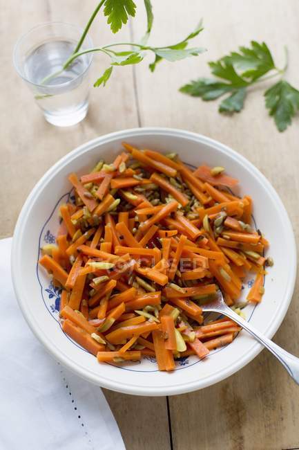 Curry de zanahoria en tazón blanco con cuchara sobre superficie de madera - foto de stock