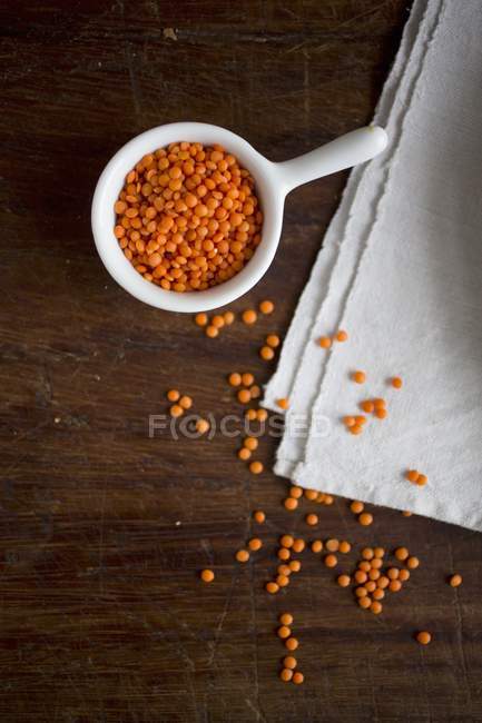 Vista dall'alto di lenticchie rosse in ciotola e su stoffa — Foto stock