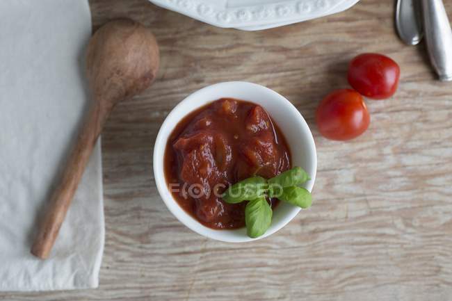 Molho de tomate com manjericão na placa branca sobre a superfície de madeira — Fotografia de Stock