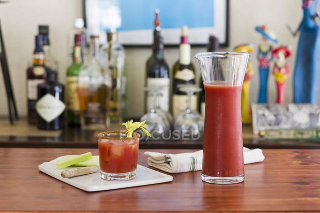 Un classico Bloody Mary drink con sedano su un tavolo con un home bar sullo sfondo — Foto stock