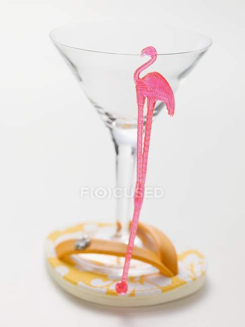 Closeup view of empty cocktail glass with flamingo stick on thong sandal — Stock Photo